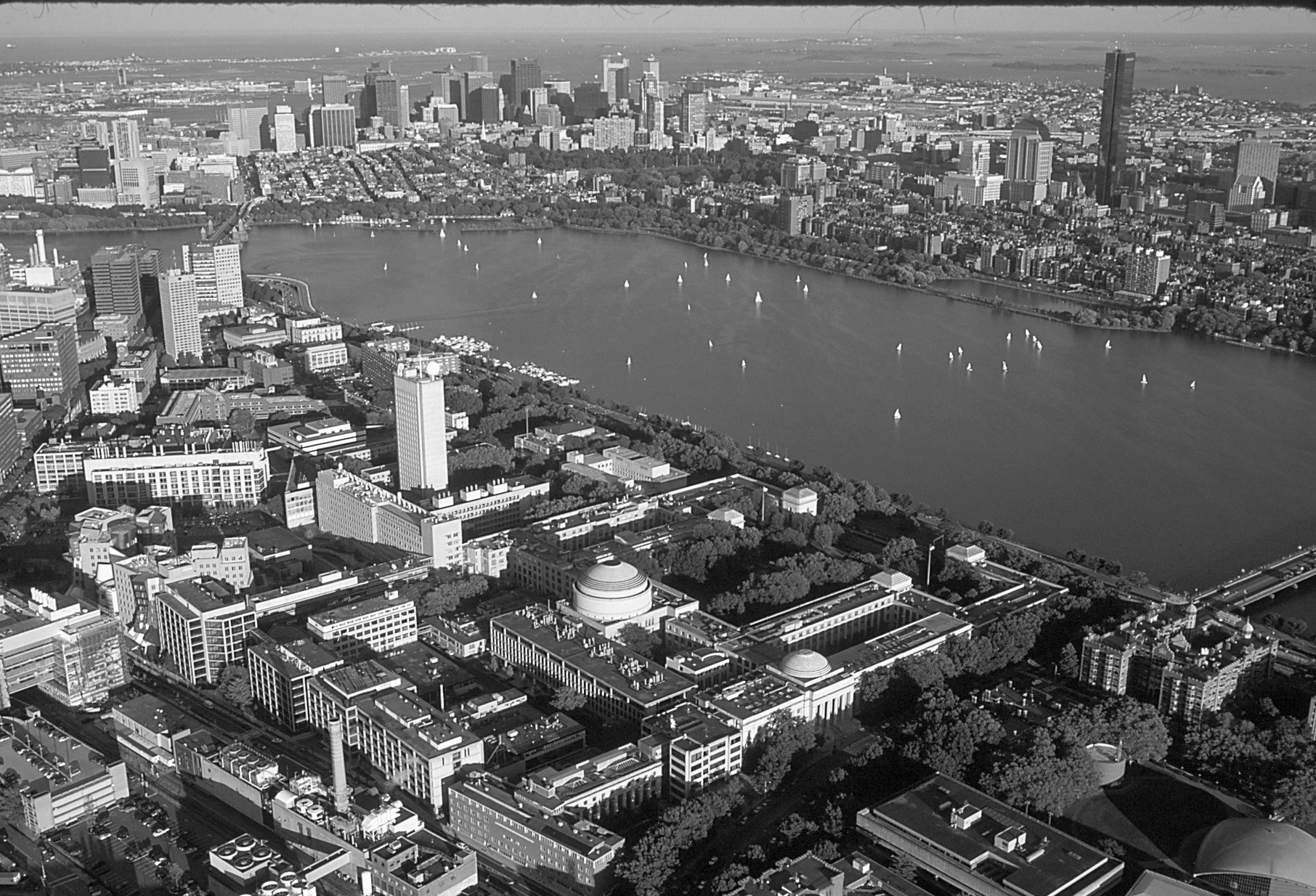 Aerial view of MITs campus along Charles River with Boston skyline in background.